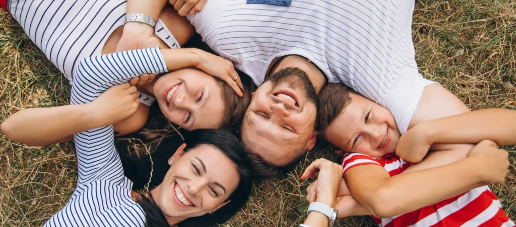 Happy family lying on grass, smiling together.