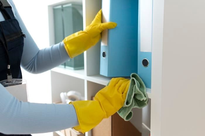 Person cleaning shelf with gloves and cloth